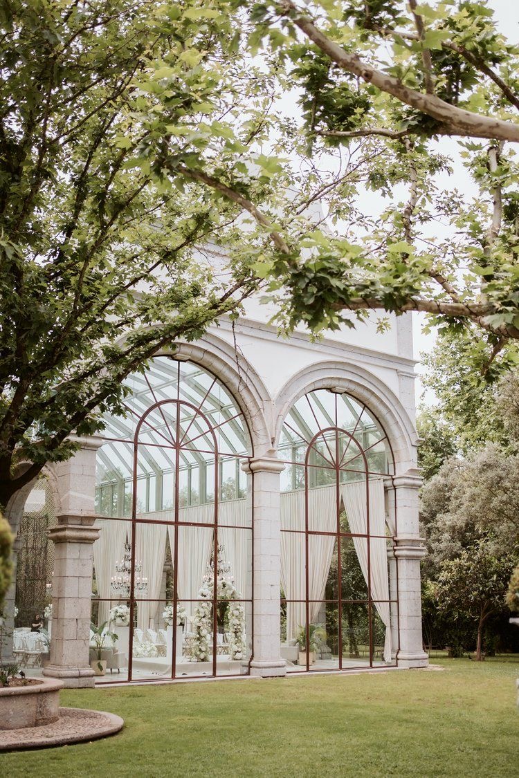 Stone and glass orangery at Solar da Levada in daylight, framed by trees and lawn.
